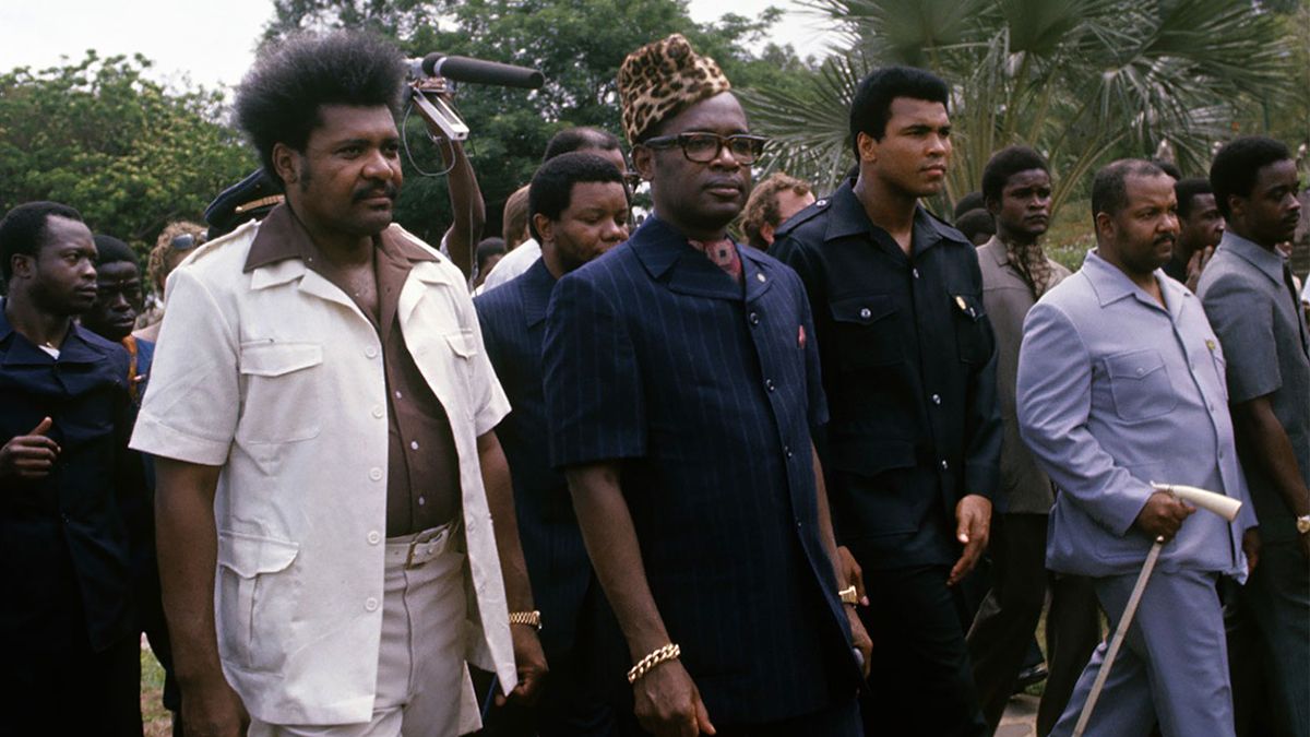 El promotor Don King (izquierda) logró que un sangriento dictador como Joseph-Désiré Mobutu (a quien, a partir de 1970, se lo conocería como Mobutu Sese Seko, centro) desembolsara 10 millones de dólares para la bolsa de los boxeadores, que fue de 5 millones para cada uno.