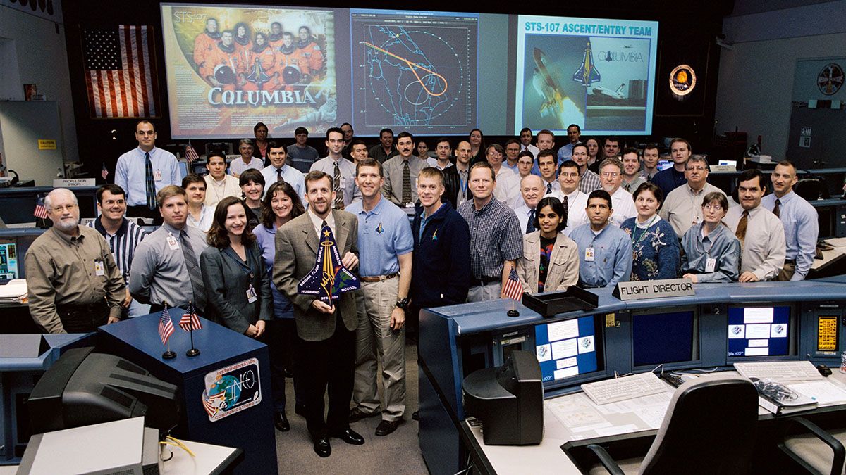 Los miembros del equipo de Ascenso / Entrada STS-107 posan para un retrato grupal en la sala de control de vuelo del transbordador (WFCR) en el Centro de Control de Misión (MCC) de Houston. El director de vuelo LeRoy Cain tiene el logo de la misión STS-107. 07 de enero del 2003. Foto: Nasa.