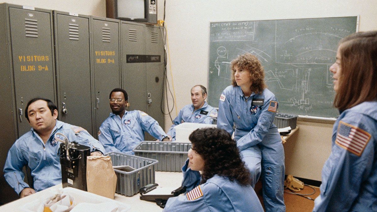 Cinco miembros de la tripulación principal para la misión STS-51L de la NASA y un miembro de la tripulación de respaldo son informados durante una sesión de entrenamiento en el Laboratorio de Maquetas e Integración del Shuttle del Centro Espacial Johnson (JSC).Crédito de la foto: NASA