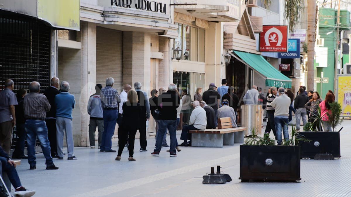 Un grupo amontonado de personas en una sucursal del banco Patagonia en la peatonal.