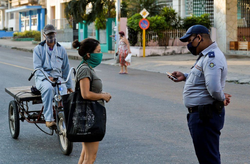 Un policía revisa la identificación de una mujer en La Habana, durante la cuarentena.YAMIL LAGE / AFP