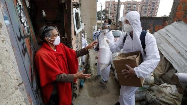 Trabajadores de la Alcaldía de Bogotá entregan víveres a una mujer en un barrio carenciado del norte de la capital de Colombia