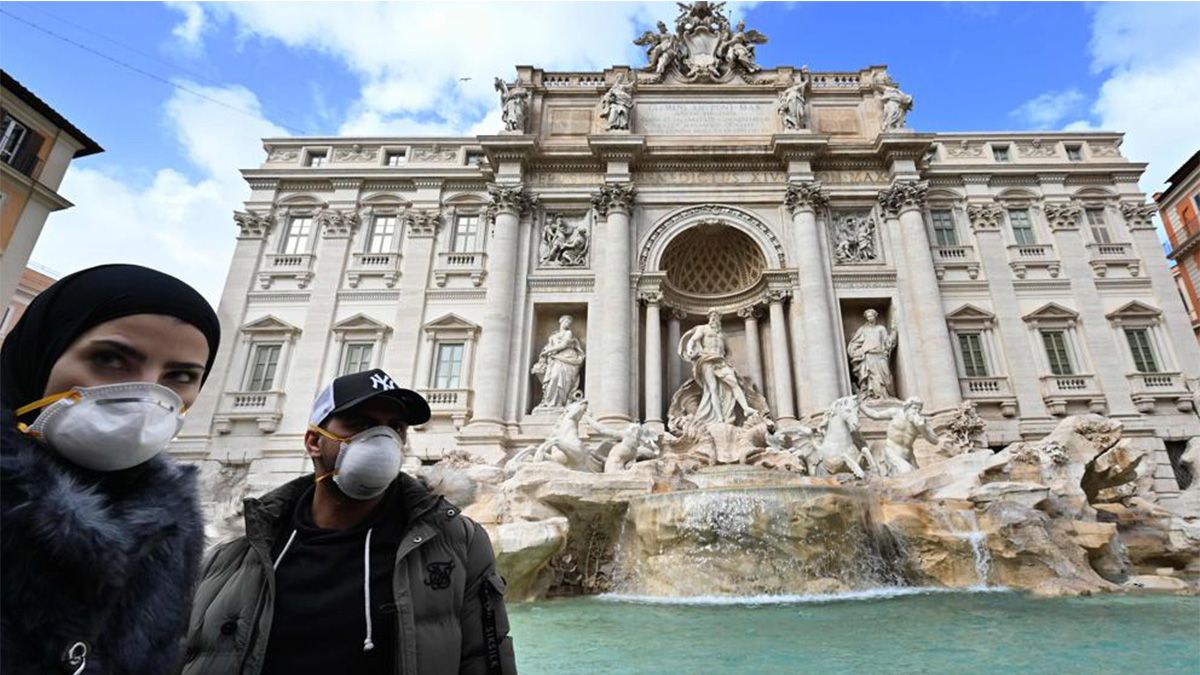 Dos turistas protegidos con máscaras en la Fontana Di Trevi en Roma - AFP