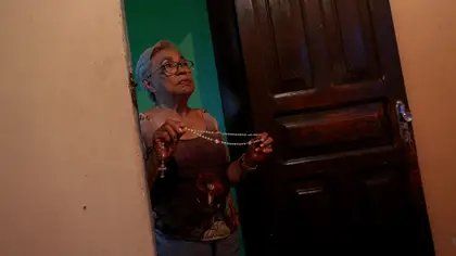 María rezando por el descanso de sus hijos y cuñados (MICHAEL DANTAS / AFP)