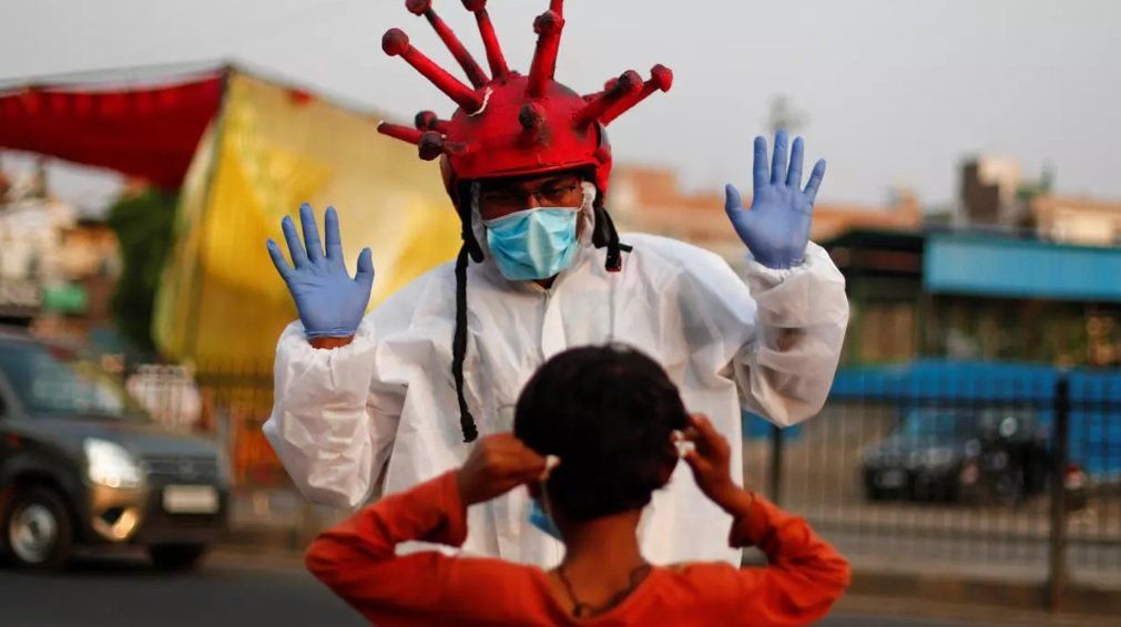 Un médico juega con un niño en la India, vestido con la forma del coronavirus