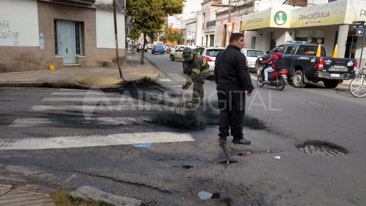 Bomberos limpian la calle tras el encendido de neumáticos durante la propuesta de los trabajadores del fútbol 5.