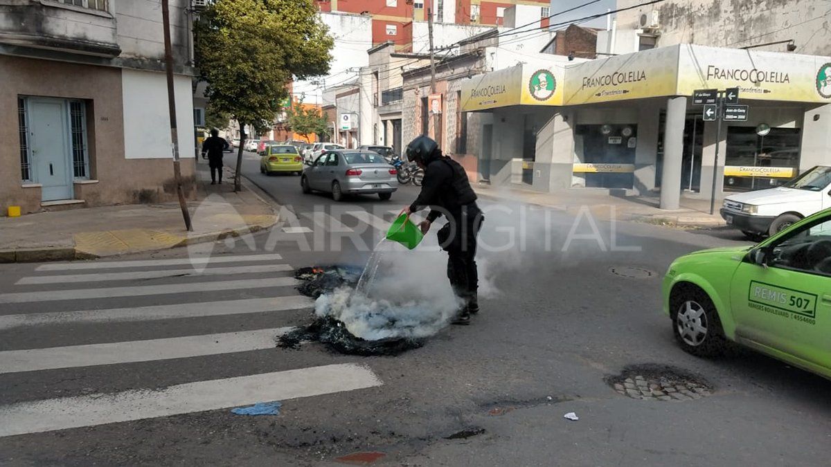 Un policía intenta apagar las llamas de un neumático encendido.