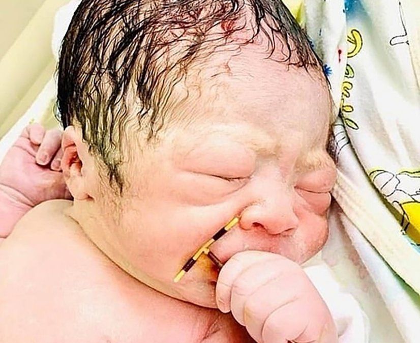 Bebé recién nacido agarrado del anticonceptivo de la madre.