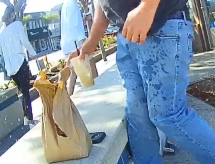 La mujer, de blanco, ya le arrojó el café hirviendo al hombre que almorzaba sentado en un banco. 