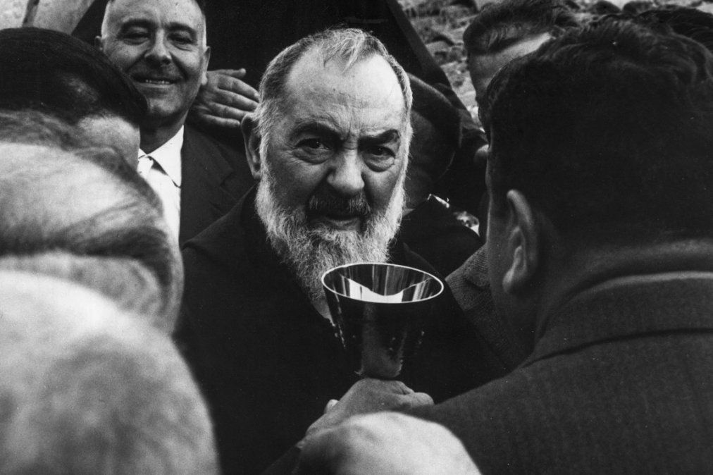 El Padre Pío camina entre los fieles con un cáliz. Década de 1960