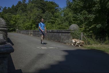 Un hombre lleva su perro con correa sobre el misterioso puente Overtoun en Dumbarton, Escocia