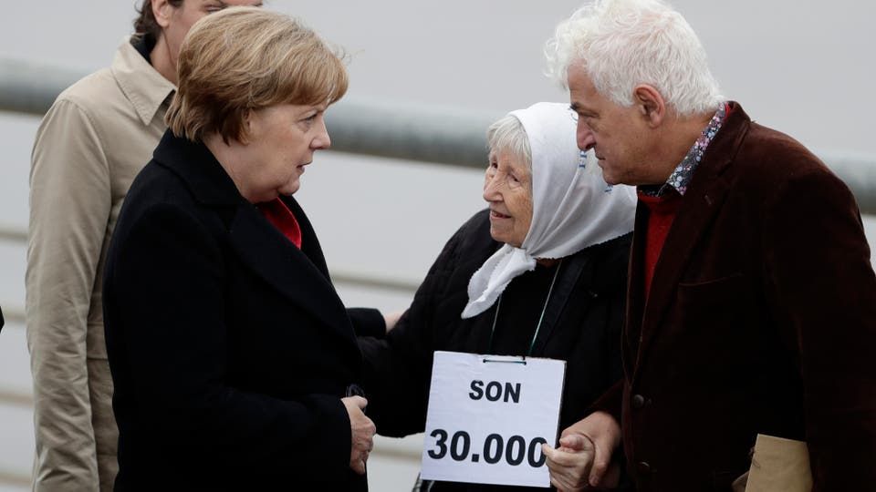 Angela Merkel habla con Vera Jarach, de Madres de Plaza de Mayo y el activista por los derechos humanos Marcelo Brodsky. Foto: AP / Victor R. Caivano
