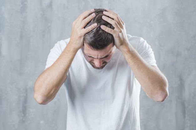 Primer plano de un hombre que sufre de dolor de cabeza contra el fondo gris