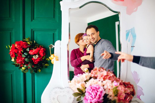 Reflection of happy parents with little girl in white mirror