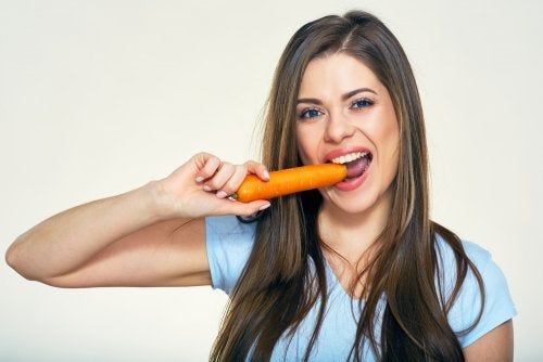 Mujer comiendo una zanahoria para evitar agresiones solares.