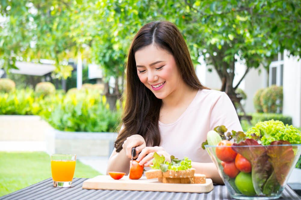 Mujer sentada a la mesa con varios alimentos.