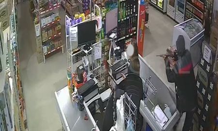 El momento en que uno de los ladrones apuntaba a la cajera del minimercado. El momento en que uno de los ladrones apuntaba a la cajera del minimercado.