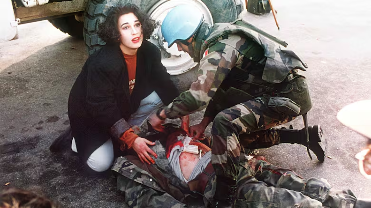 Una imagen fechada el 21 de noviembre de 1994 muestra a un soldado francés de la ONU y a una mujer brindando primeros auxilios a un soldado bosnio alcanzado por una bala de francotirador en la llamada “avenida de los francotiradores” de Sarajevo