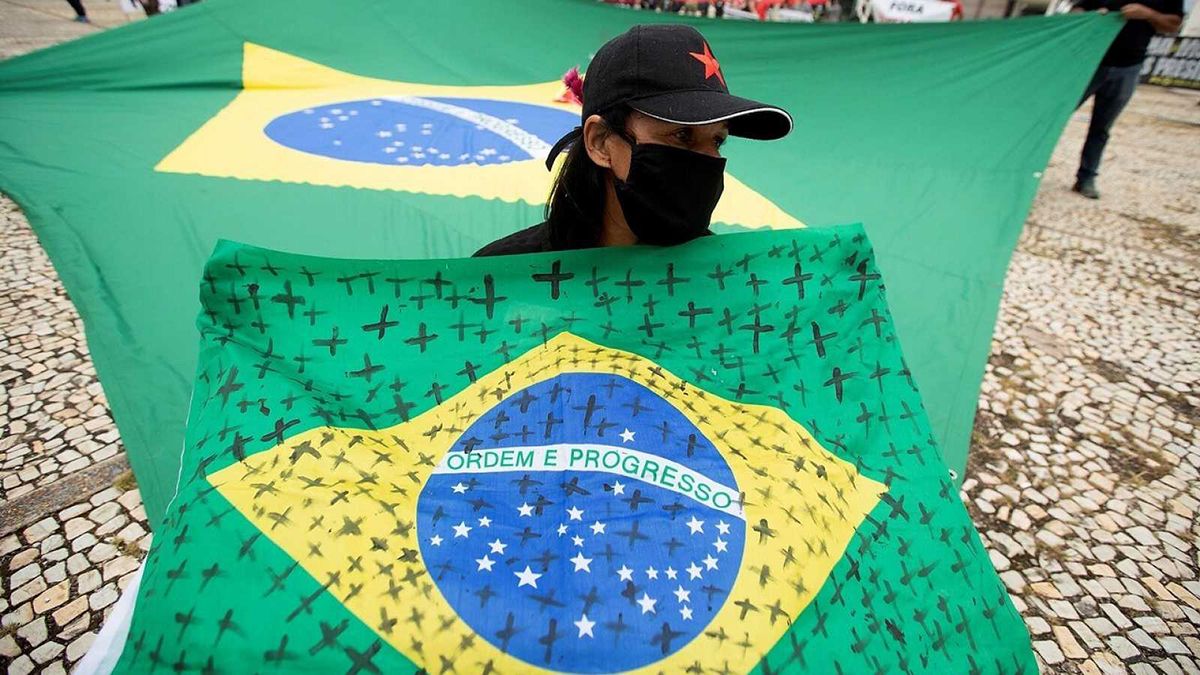 Una mujer con una bandera de Brasil con cruces por las v&iacute;ctimas del coronavirus.