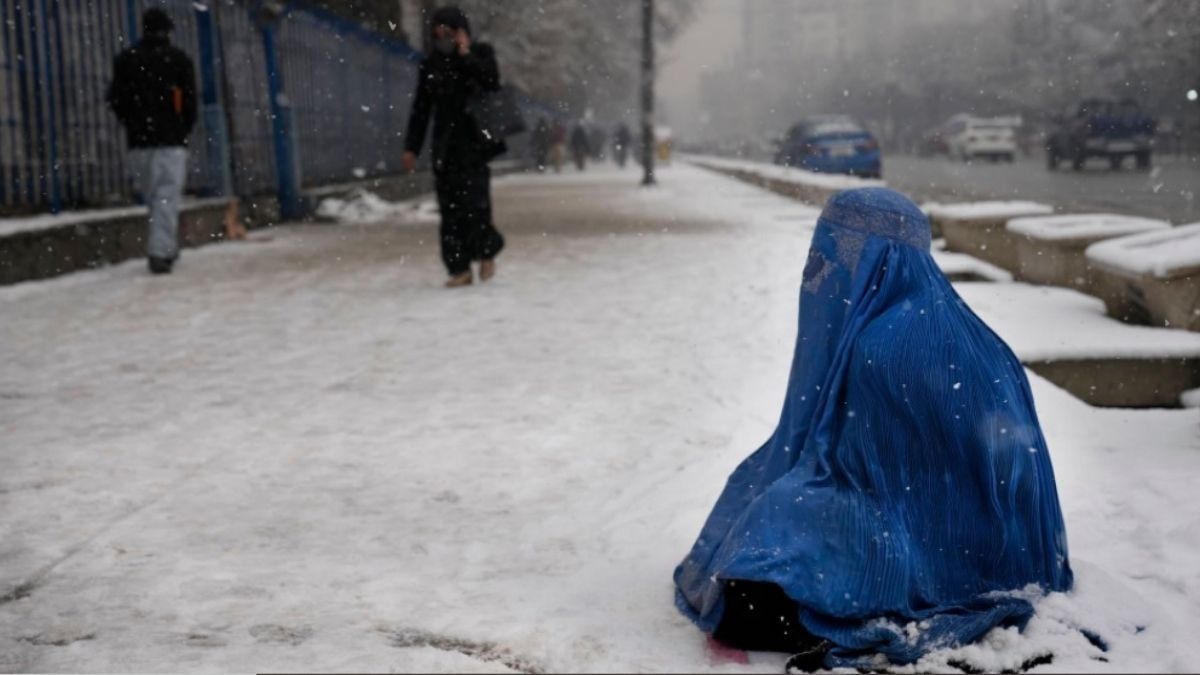 Una afgana cubierta por un burka pide limosna sentada en la nieve en una calle de Kabul el 6 de febrero.