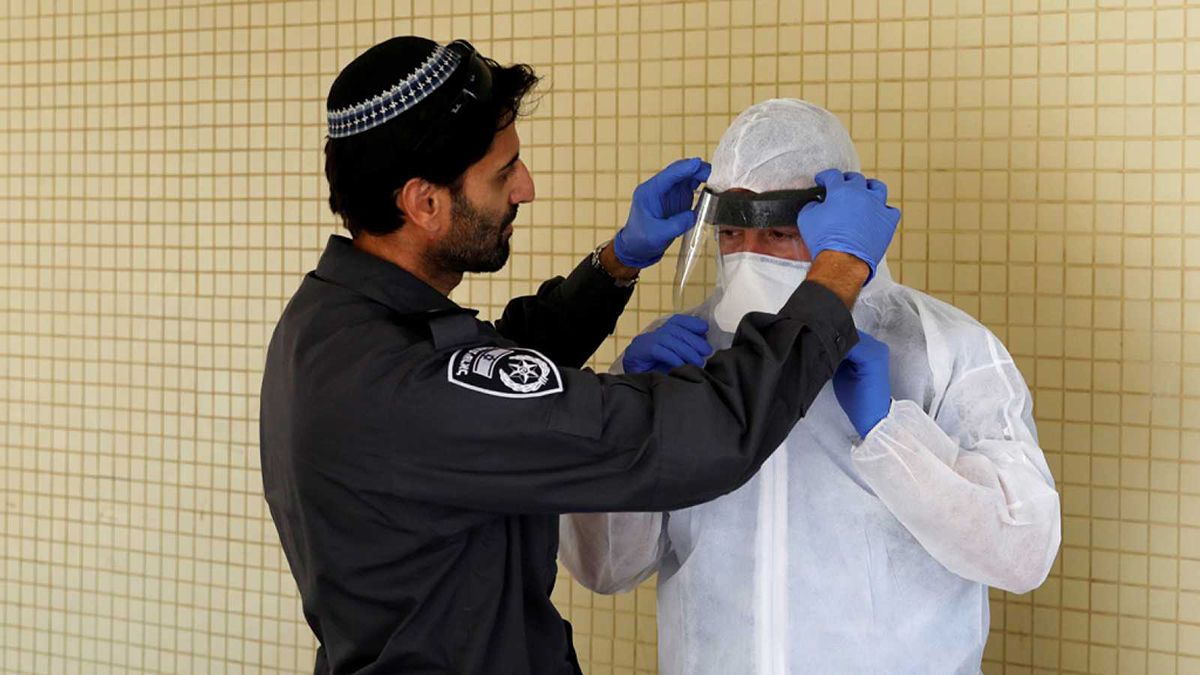 Un encargado de la seguridad de Israel acomoda una máscara de prevención contra el coronavirus.