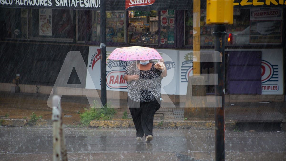 En la zona de la Terminal de Ómnibus, una mujer cruza la calle con un paraguas en medio de la intensa lluvia que se desató en la capital provincial a media mañana.