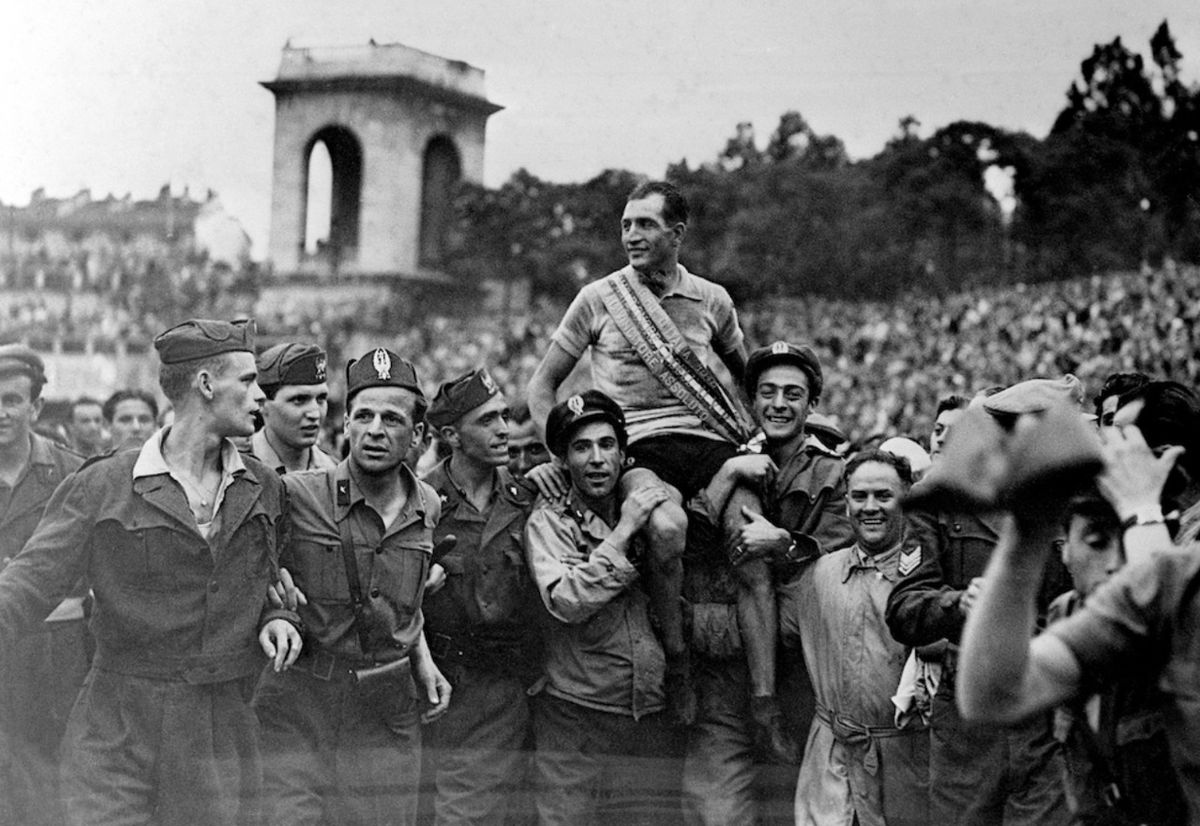 El 7 de julio de 1946, Gino ganó por tercera y última vez el Giro d’Italia. Le faltaban 11 días para cumplir 32 años, y fue su primera gran conquista una vez finalizada la Segunda Guerra Mundial. En la foto, es llevado en andas tras la 17ª y última etapa, entre Mantua y Milán.