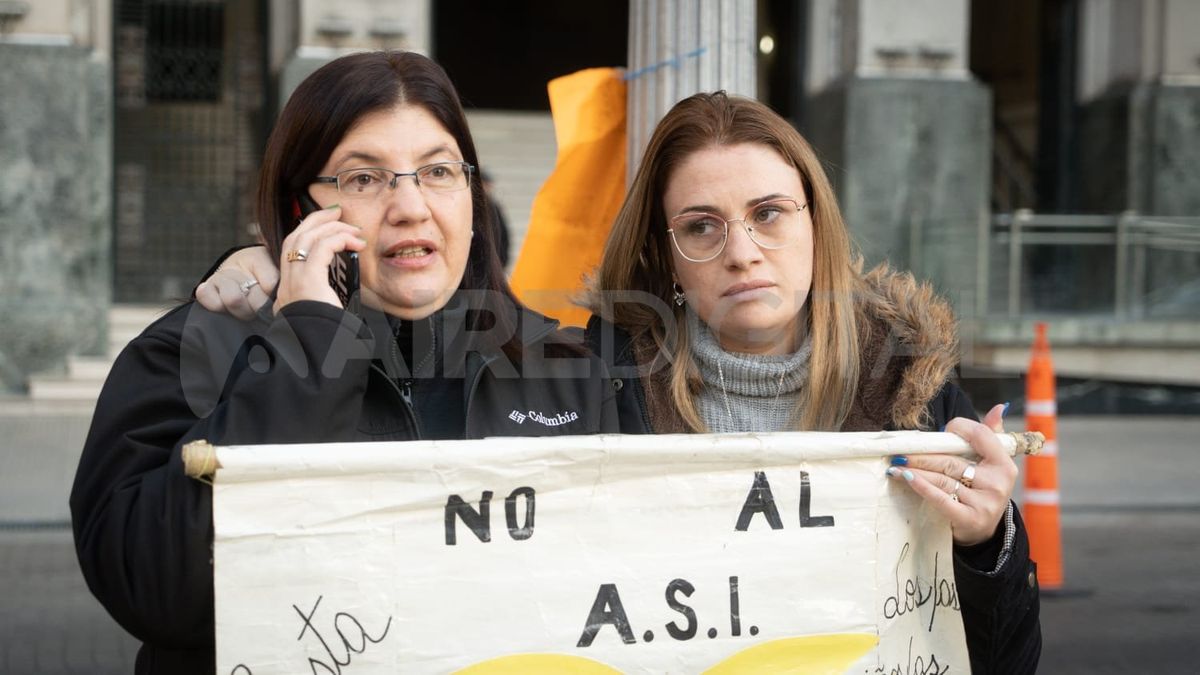 La mamá y la hermana de M en Tribunales, antes de empezar el juicio, con el cartel con el que empezaron a hacer el reclamo.