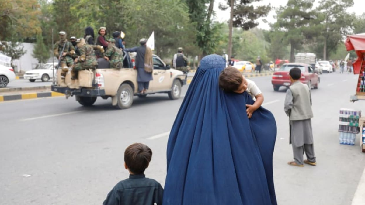 Una mujer afgana camina con sus hijos en el aniversario de la caída de Kabul en una calle de Kabul