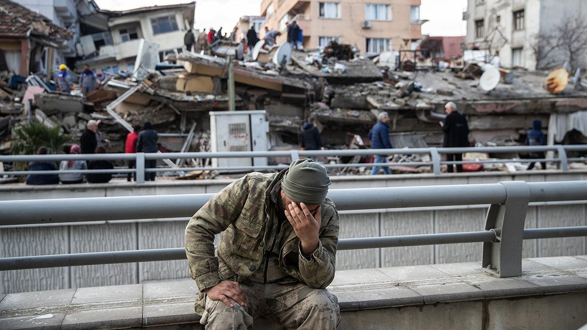 Un hombre se agarra la cara, sentado al lado de los escombros de un edificio en Turquía, tras el feroz terremoto.