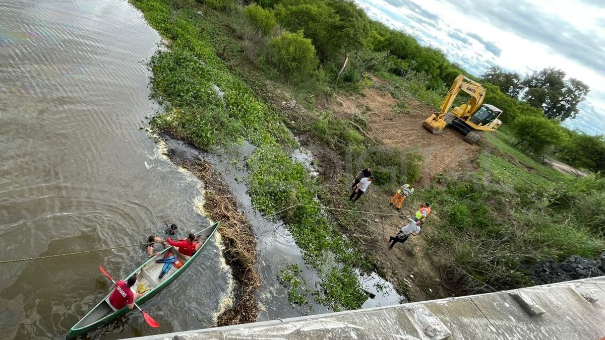 Con una máquina retroexcavadora intentan sacar el camión del arroyo.