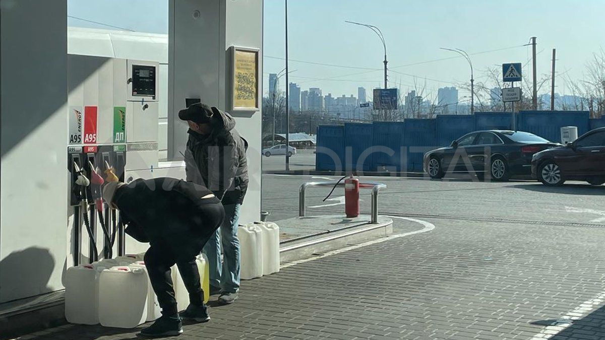 Dos hombres cargando nafta en bidones ante la falta de combustibles en medio de la guerra.