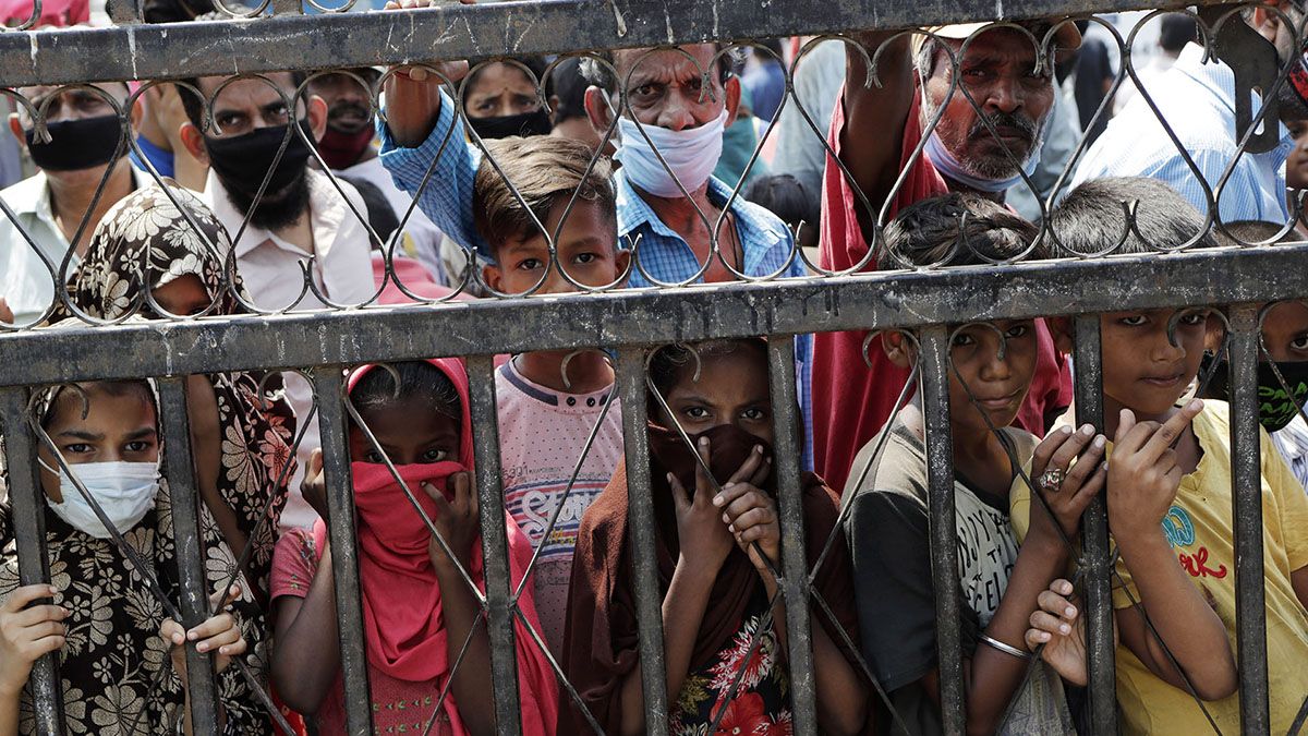 Niños esperan para recibir alimentos gratuitos en un barrio marginal durante la cuarentena por el coronavirus en Mumbai