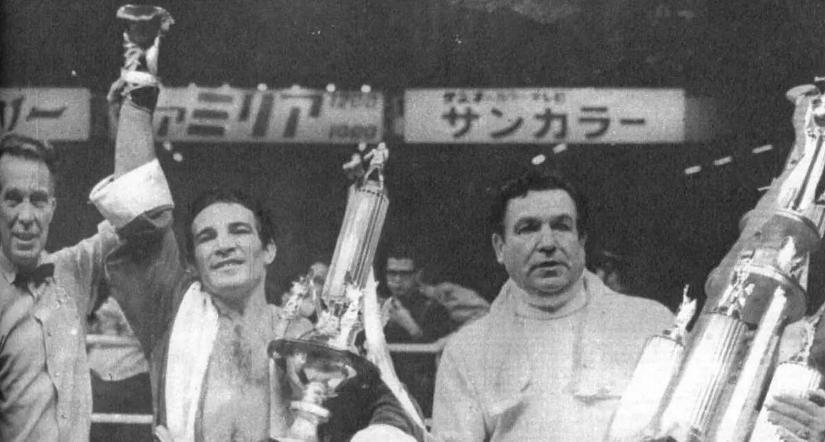 El árbitro estadounidense Nick Pope levanta la mano y consagra campeón a Nicolino, quien posa junto a su maestro, Francisco Paco Bermúdez, uno de los inolvidables entrenadores de la historia del boxeo nacional, y titular del Mocoroa Boxing Club de Mendoza, al que Locche ingresó acompañado por su madre cuando solo tenía 8 años. El árbitro estadounidense Nick Pope levanta la mano y consagra campeón a Nicolino, quien posa junto a su maestro, Francisco Paco Bermúdez, uno de los inolvidables entrenadores de la historia del boxeo nacional, y titular del Mocoroa Boxing Club de Mendoza, al que Locche ingresó acompañado por su madre cuando solo tenía 8 años.