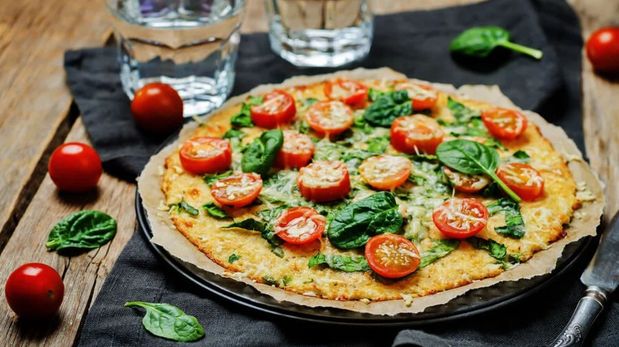La receta de pizza de coliflor con tomate, mozzarella y albahaca.