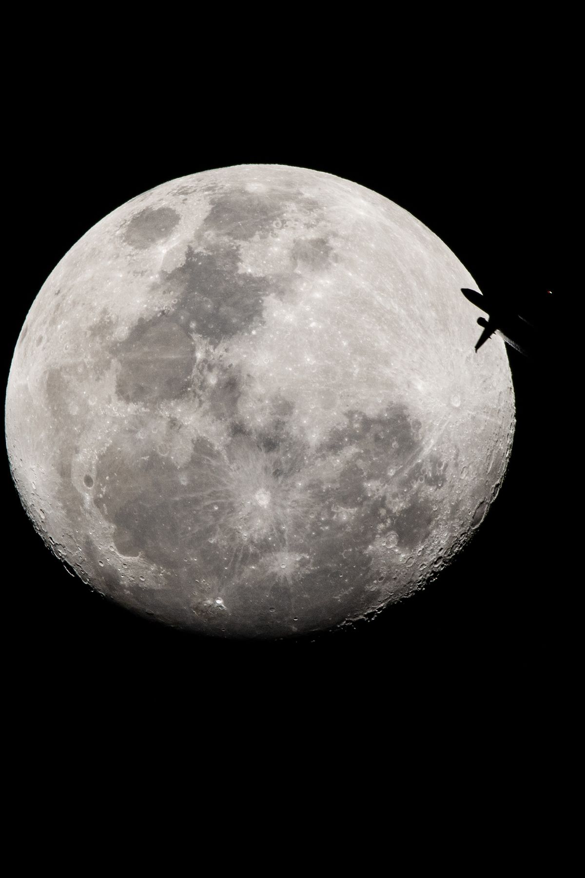 Un avión que se dirige desde Buenos Aires hasta Lima, Perú, pasa por delante de la Luna vista desde la ciudad de Santa Fe, Argentina. Se puede ver el ingreso del avión a la luz de la Luna, con el humo de una turbina.