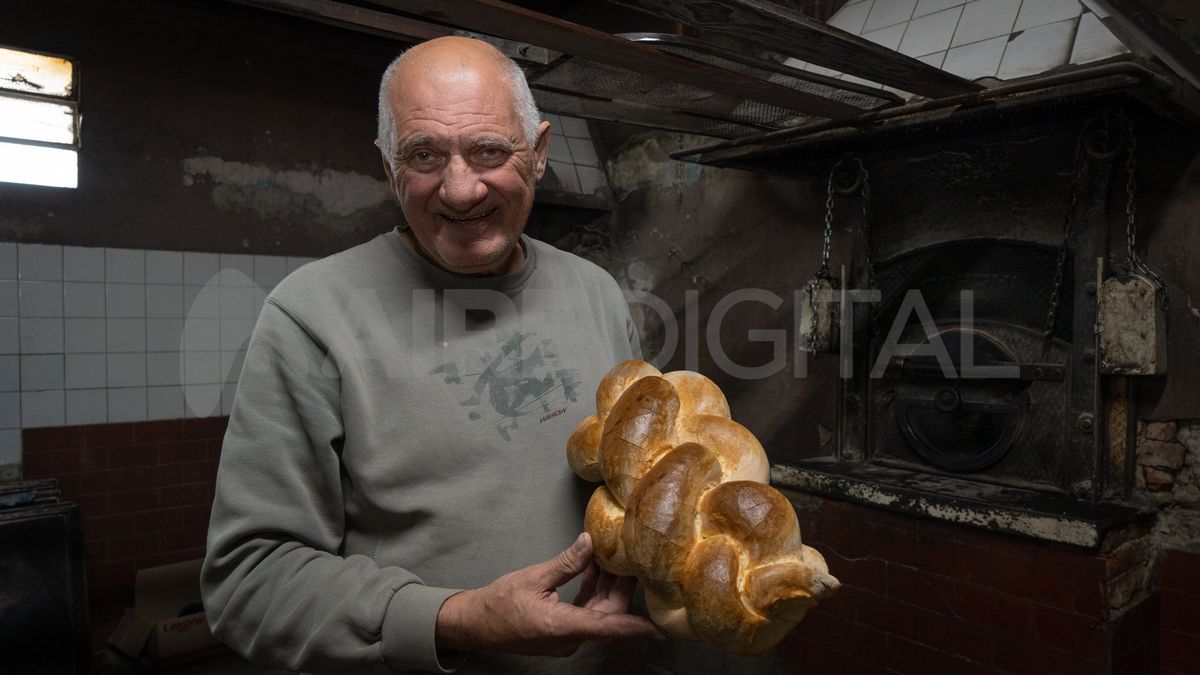 El panadero Bernardino Urban sostiene el pan jalá que elaboró en su horno, que hace rato cumplió medio siglo.