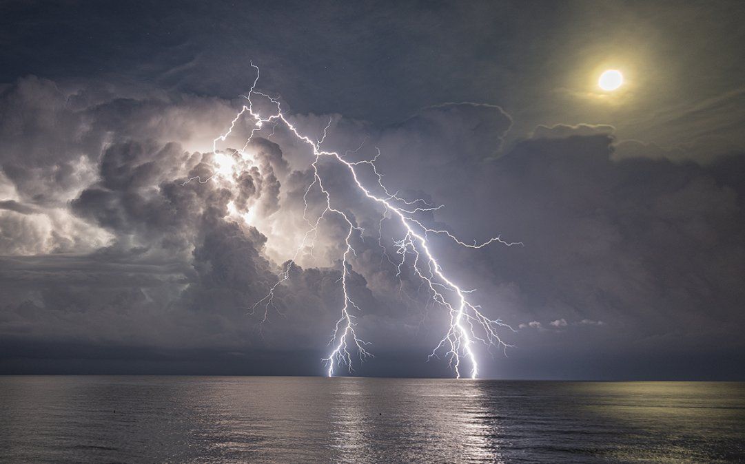 Tormenta multicélula. Un rayo positivo al lado de la Luna.