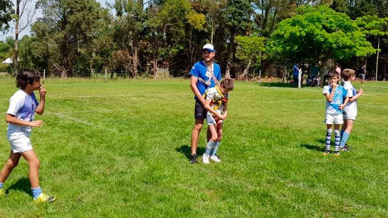Niño juega al rugby por primera vez con ayuda de un arnés