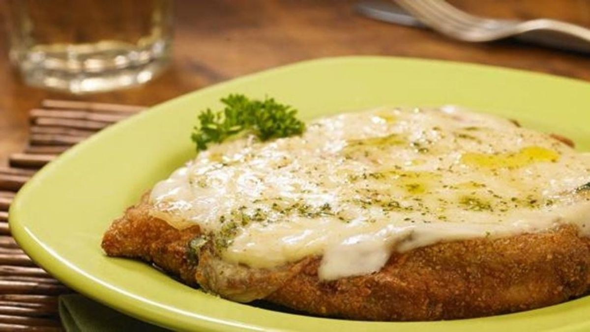 Un golpe de horno fuerte al final de la cocción gratina los lácteos de forma inmediata, reteniendo los jugos naturales del pollo sin ablandar el rebozado crocante de la milanesa.