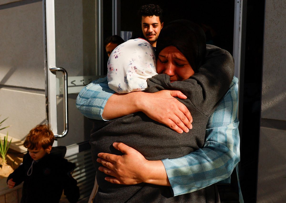Las mujeres se abrazan mientras los palestinos con pasaportes extranjeros llegan al cruce fronterizo de Rafah con Egipto