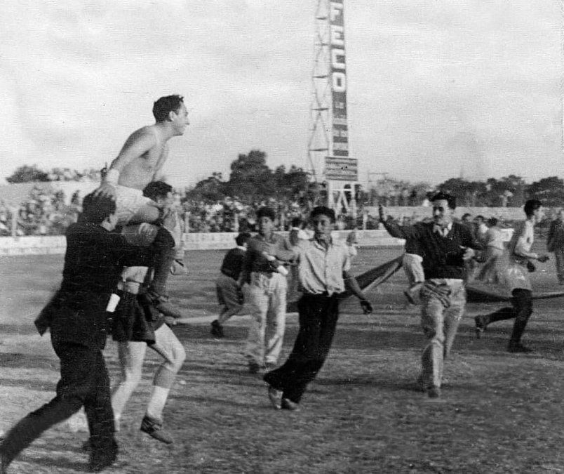 Gaetan alzando a Olivera en el Brigadier López, con una de las viejas torres de iluminación de fondo.