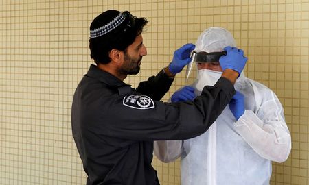 Un encargado de la seguridad de Israel acomoda una máscara de prevención contra el coronavirus. Un encargado de la seguridad de Israel acomoda una máscara de prevención contra el coronavirus.