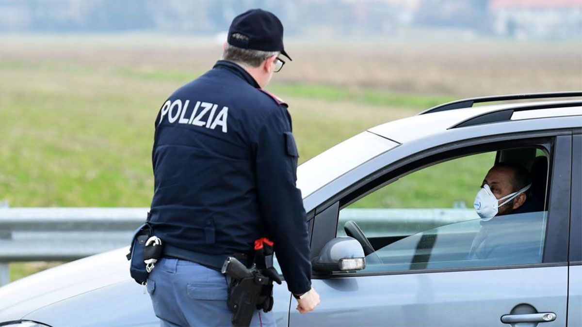 Un polic&iacute;a italiano habla con un hombre a la entrada de Casalpusterlengo