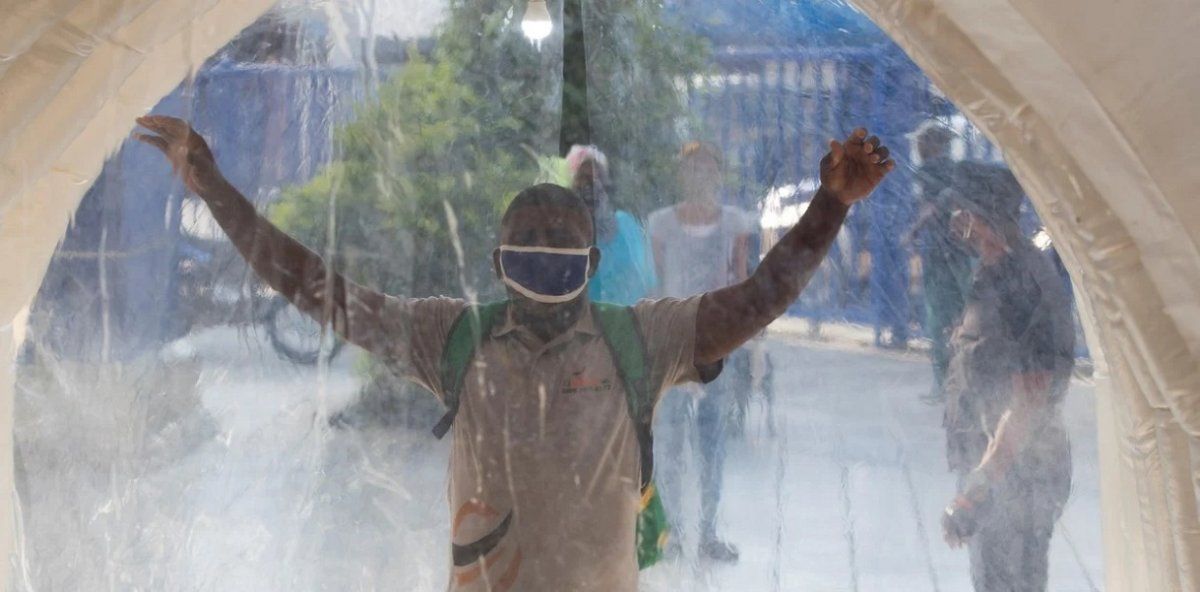 Una persona cruza un t&uacute;nel para su desinfecci&oacute;n debido a la crisis del coronavirus