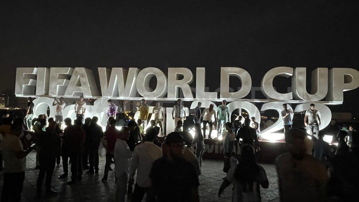 Letras corpóreas iluminadas que dicen "Fifa World Cup Qatar 2022", en donde miles de turistas se toman fotografías.