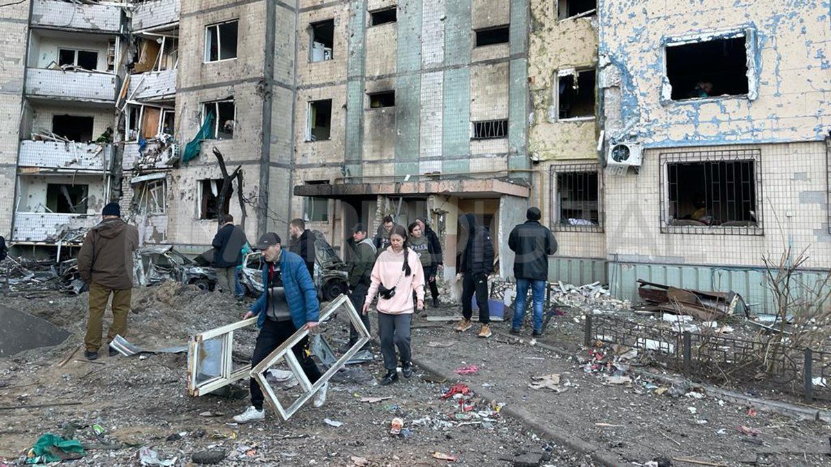 La gente retira escombros de un edificio atacado por los rusos y prepara un refugio para la noche en el centro de Kiev.