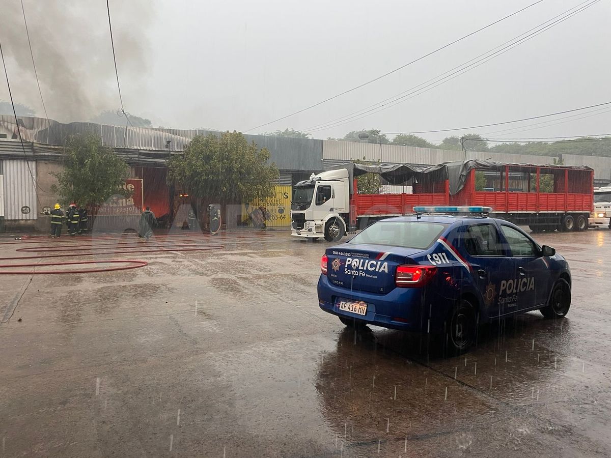 Personal policial y de bomberos trabajan bajo la intensa lluvia en apagar el incendio. Personal policial y de bomberos trabajan bajo la intensa lluvia en apagar el incendio.