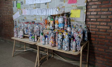 Los alumnos de quinto primera están colocando los folletos dentro de botellas vacías de plástico y de esa forma realizan ladrillos reutilizables. Los alumnos de quinto primera están colocando los folletos dentro de botellas vacías de plástico y de esa forma realizan ladrillos reutilizables.