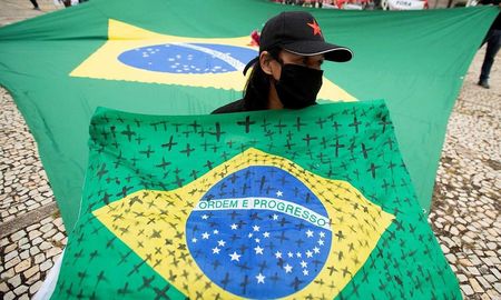 Una mujer con una bandera de Brasil con cruces por las víctimas del coronavirus. Una mujer con una bandera de Brasil con cruces por las víctimas del coronavirus.